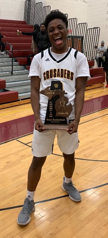 King Crusader Boys Basketball Player holding District Champion trophy 